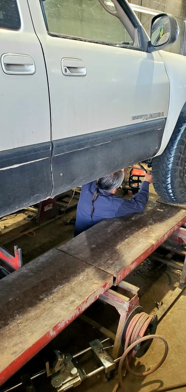 Technician working on truck suspension underneath a vehicle