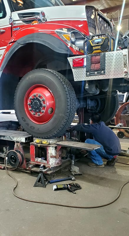 Technician servicing a red fire truck in the Largo Frame shop